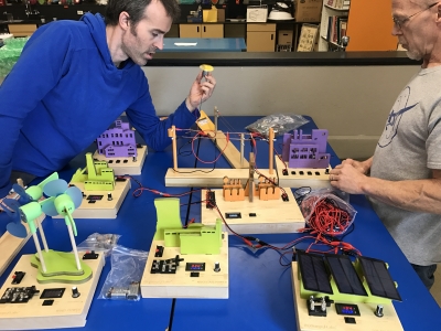 Two teachers sitting at a table working together to build a miniature clean energy power grid for students to learn about clean energy and climate solutions.