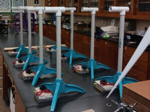 Two rows of Kidwind turbine models with their student materials sit on a lab table