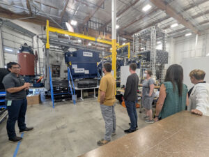 Teachers look at a Vestas Wind Turbine Training station which has steps leading upt to a blue container.
